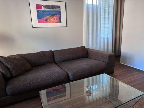 a living room with a brown couch and a glass table at Local family home Copenhagen close to city center in Copenhagen