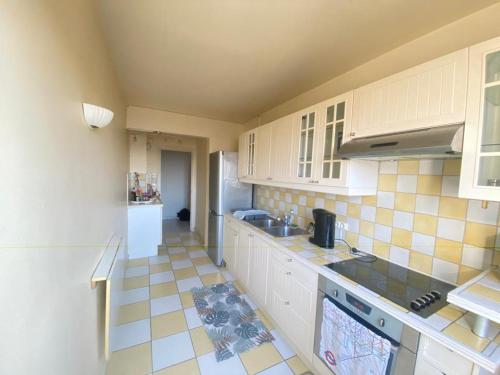 Il comprend une cuisine avec des placards blancs et du carrelage. dans l'établissement Appartement familial proche de Paris, au Bourget