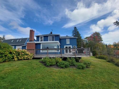 a blue house with a deck on a lawn at Pound House in Hancock