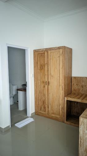 a bathroom with a wooden cabinet and a toilet at Sujiwa Ubud Hotel & Villa in Ubud
