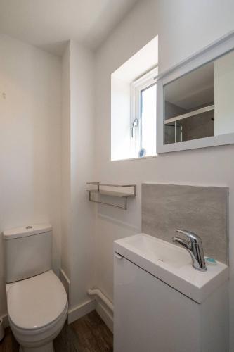 a white bathroom with a toilet and a sink at 1 Buxlow Cottages in Aldringham