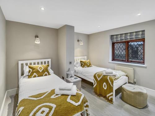 a bedroom with two beds and a window at One Grooms Cottage, Dunster in Dunster