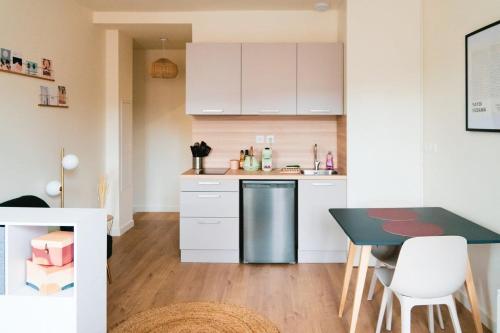 une cuisine avec des placards blancs et une table noire dans l'établissement Bloom living - T1 standing - Hyper centre, à Toulouse