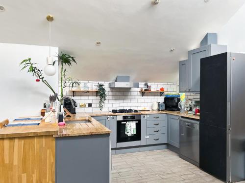 una cocina con electrodomésticos de acero inoxidable y armarios grises en Beautiful&quite warehouse, en Londres