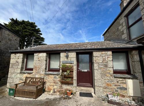 a stone house with a bench in front of it at Thea Cottage in Perranuthnoe