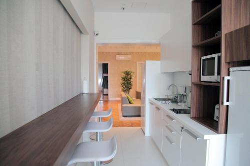 a kitchen with white cabinets and a counter with white chairs at Hostel Karavan Inn in Belgrade
