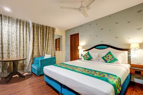 a bedroom with a large bed and a blue chair at Treebo Blak & Wite Rk Beach in Visakhapatnam