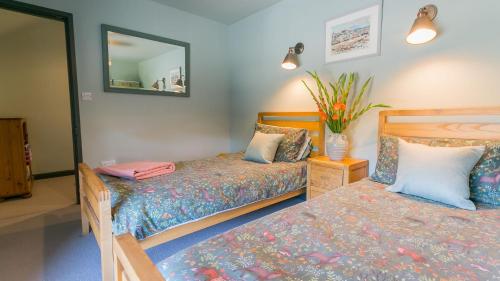 a bedroom with two beds and a mirror at 7 Seaview in Moelfre