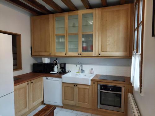 kuchnia z drewnianymi szafkami i zlewem w obiekcie Le Relais de Lyons w mieście Lyons-la-Forêt