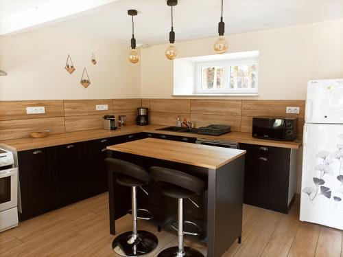 une cuisine avec des armoires noires et un comptoir en bois dans l'établissement Hors du temps gîte nature, à Merlines