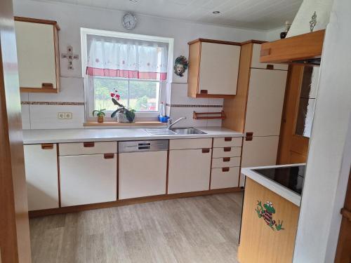 a kitchen with white cabinets and a sink and a window at Ferienhaus Melchartboden in Paal