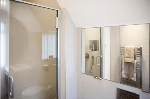 a bathroom with a shower with a mirror and a sink at Oldfield Cottage within walking distance of pub and sea in West Itchenor