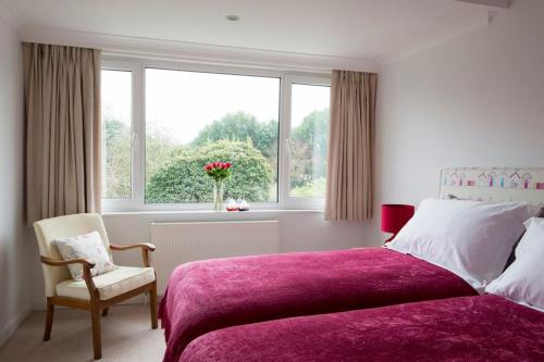a bedroom with a bed and a chair and a window at Oldfield Cottage within walking distance of pub and sea in West Itchenor
