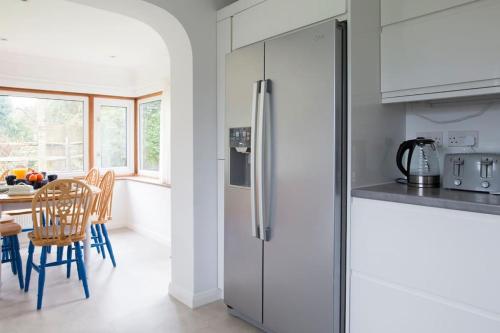a kitchen with a refrigerator and a table with chairs at Oldfield Cottage within walking distance of pub and sea in West Itchenor