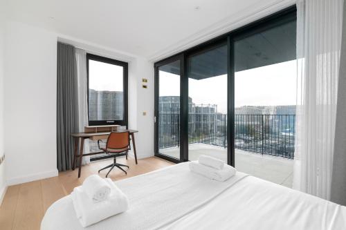 a bedroom with a bed and a desk and large windows at Kings Cross - Luxury 3 Bed Apartment, Private Balcony in London