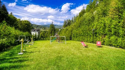 a yard with chairs and a playground in the grass at Apartament SPA 56 Resort Kozubnik blisko Szczyrk - 5D Apartamenty in Porąbka