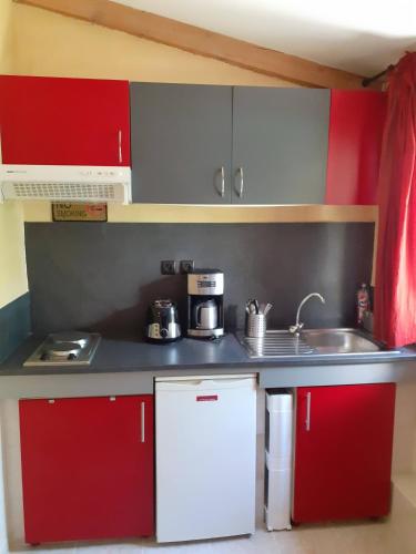 a kitchen with red and white cabinets and a sink at Tiny house in Avignon