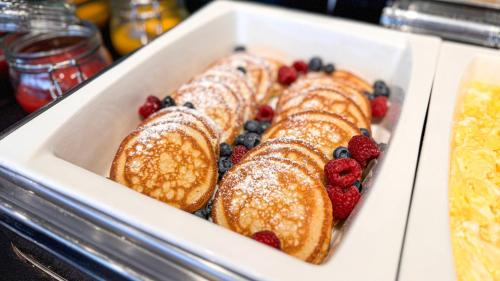 a tray of pastries with berries and powdered sugar at Hotel Victor Pruszków DeSilva in Pruszków