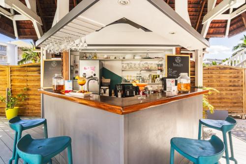 a bar with two blue stools at a counter at Hôtel Exsel Ermitage in Saint-Gilles les Bains