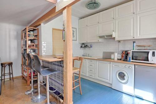 une cuisine avec des armoires blanches et une table et des chaises dans l'établissement Les bamboos de Malakoff Paris, à Malakoff