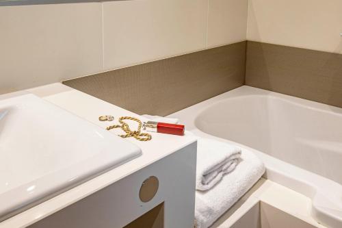 a bathroom with a white tub and a white sink at Mercure Angoulême Hôtel de France in Angoulême