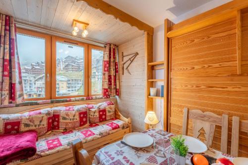 une chambre avec un canapé, une table et une fenêtre dans l'établissement Ski In-Out - Heart of Val Thorens Cosy Apartment, WiFi 215, à Val Thorens