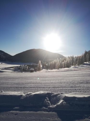 a snow covered field with the sun in the background at Ferienhaus Melchartboden in Paal
