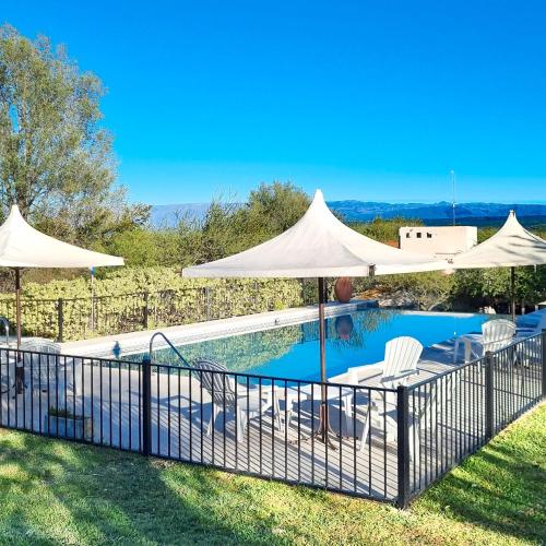 a swimming pool with two umbrellas and chairs next to a pool at Posada La Soñada in Villa General Belgrano
