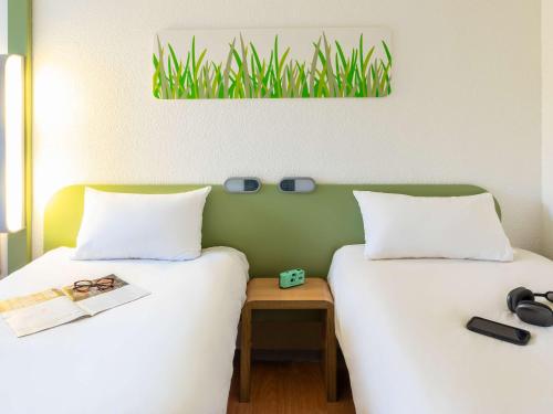 two beds sitting next to each other in a room at ibis budget Compiègne Centre-Ville in Compiègne