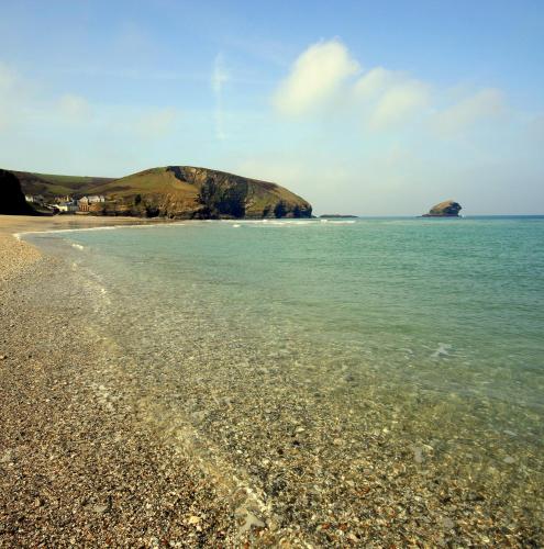 a beach with a rocky shore with a mountain in the background at Tehidy Holiday Park in Illogan