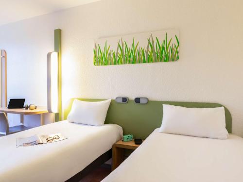 two beds sitting next to each other in a room at ibis budget Compiègne Centre-Ville in Compiègne