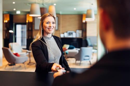 a woman standing at a table talking to a man at harry's home Villach hotel & apartments in Villach