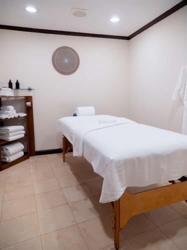 a bedroom with a white bed and a shelf with towels at MS Milenium Monterrey Curio Collection by Hilton in Monterrey