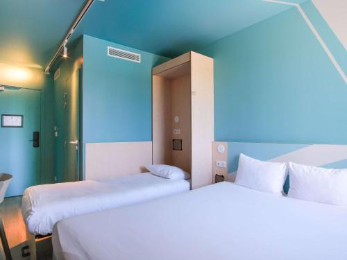 two beds in a room with blue and green walls at ibis budget Toulouse Labège in Labège