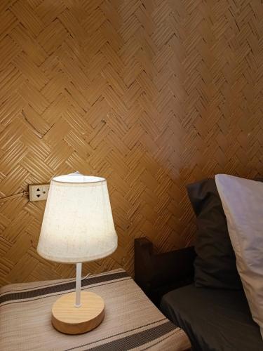 a lamp sitting on a table next to a bed at Bucana Beach House North El Nido in El Nido