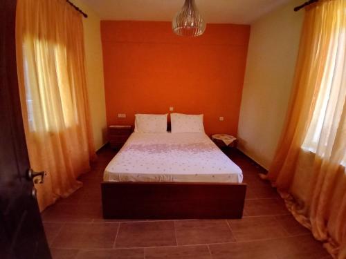 a bedroom with a bed with orange walls and curtains at Καραναστάση in Elassona