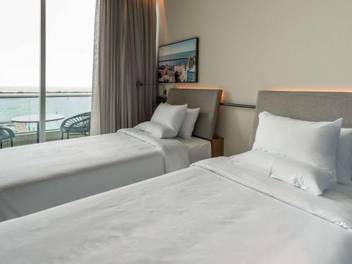 a hotel room with two beds and a balcony at Novotel Recife Marina in Recife