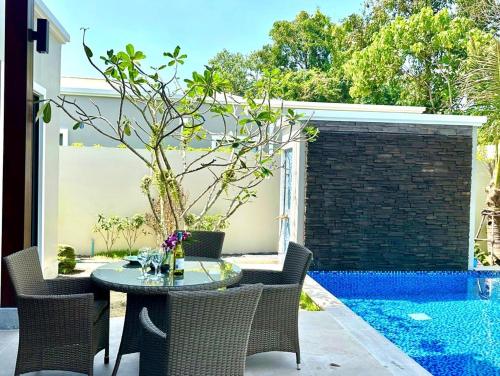 a patio with a table and chairs next to a pool at Villa Aura 4 bd in Bang Tao Phuket in Phuket Town