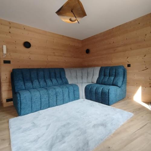 - un canapé bleu dans une chambre dotée de murs en bois dans l'établissement Hearth of Courchevel - La Tania, à Courchevel