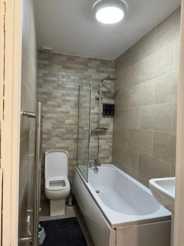 a bathroom with a tub and a toilet and a sink at Icon Residencia Apartment in Manchester