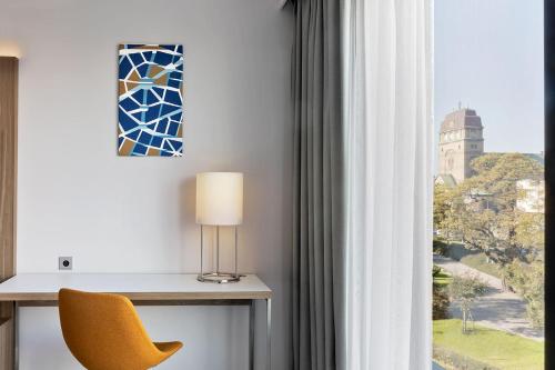 a room with a yellow chair and a window at Courtyard by Marriott Szczecin City in Szczecin