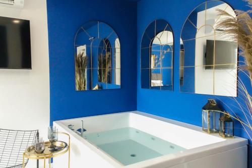 une baignoire dans une salle de bain avec des murs bleus et des miroirs dans l'établissement Kāma, à Bari Palese