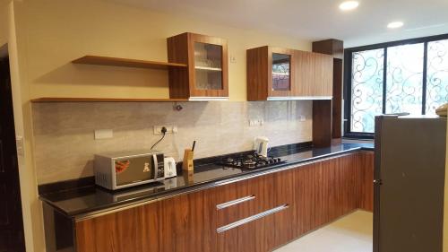 a kitchen with wooden cabinets and a sink and a microwave at Aquamarine Holidays Goa 2BHK Service Apartment 1 in Arpora