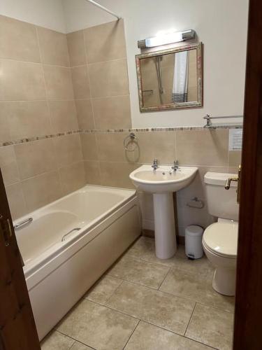 a bathroom with a tub and a sink and a toilet at Poppy Cottage - Cedar Park in Grimsby