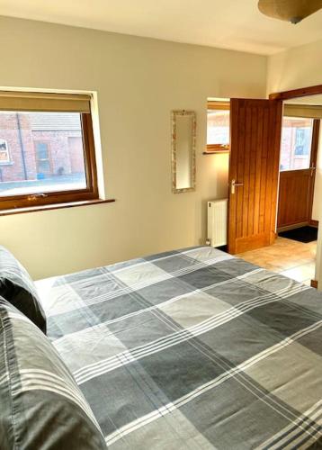 a bedroom with a bed with a blue and white blanket at Poppy Cottage - Cedar Park in Grimsby