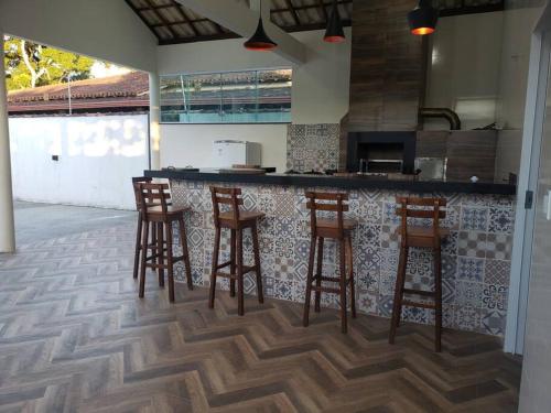 a kitchen with four bar stools and a counter at Casa aconchegante em Caravelas Abrolhos BA in Caravellas