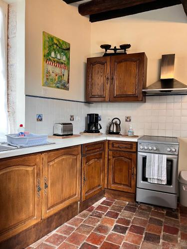 - une cuisine avec des placards en bois et une cuisinière dans l'établissement Appartement Meneau, à La Charité-sur-Loire