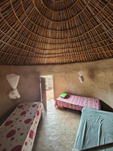 a room with two beds and a straw roof at Campement Chez Doba in Dande