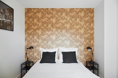 - une chambre avec un lit et deux oreillers noirs dans l'établissement New-York New-York : fibre Wifi/Linge/Parking, à Châteaubriant