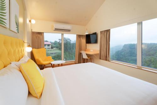a hotel room with a large bed and large windows at Bloom Hotel - Lonavala Khandala in Khandala